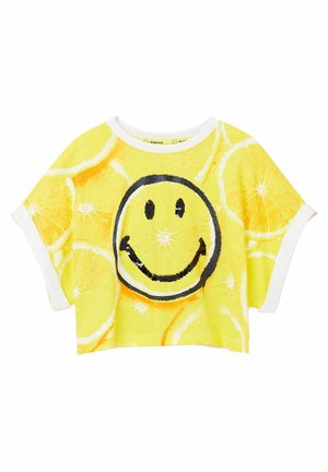 Gele cropped t-shirt met patroon van citroenschijfjes en een groot zwart omlijnd glimlachend gezicht van pailletten aan de voorkant, met wit afgewerkte mouwen en kraag.