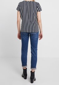 Marineblauw en witte gestreepte korte mouw top, gecombineerd met lichtblauwe denim jeans met opgerolde mouwen en zwarte enkellaarzen.