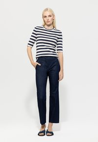 Striped navy and white top, fitted at the waist; dark denim wide-leg pants; soft sandals with a textured strap. Simple, casual outfit.