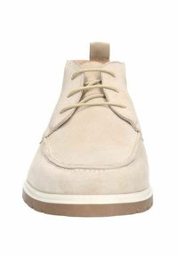 Chaussure en suède beige avec un bout rond, un laçage et une semelle texturée. Présente une semelle extérieure en caoutchouc clair contrastant et une languette au talon.