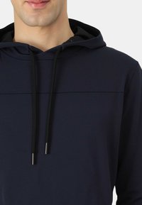 Felpa con cappuccio blu navy dalla texture liscia, dotata di coulisse nera con estremità argentate, progettata con un dettaglio di cucitura sottile sul petto.