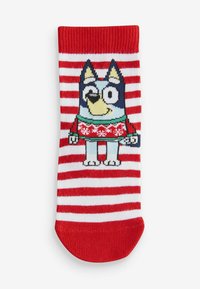 Chaussette d'enfant, rayures rouges et blanches, avec un chien en dessin animé portant un pull vert à motif festif. Bord élastique, tissu tricoté, hauteur cheville.