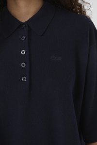 Tricou polo bleumarin cu guler cu rever, având șase nasturi în față și un logo discret embosat. Textură moale a materialului.