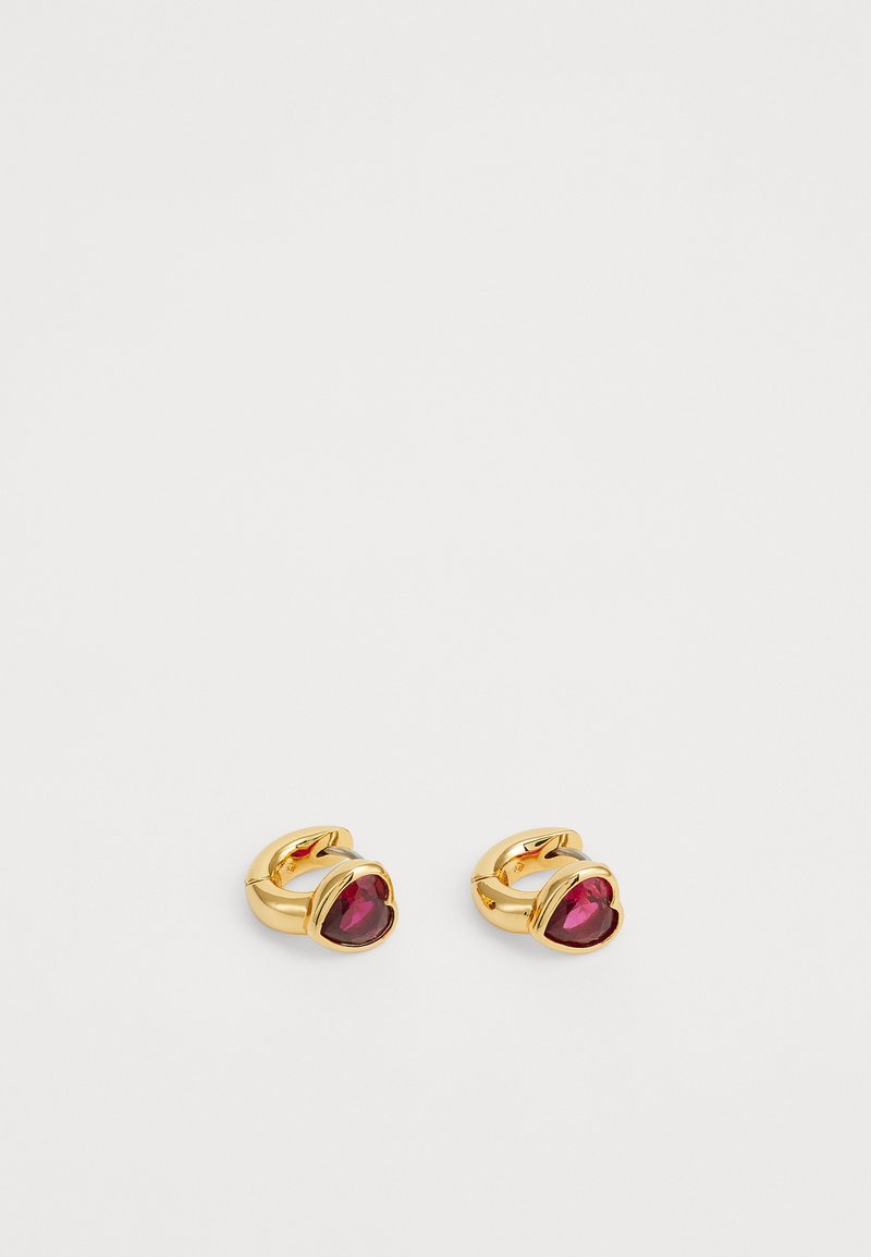 Gold-tone earrings featuring a heart-shaped, deep red gemstone set in a smooth, curved design. Polished finish with subtle detailing.