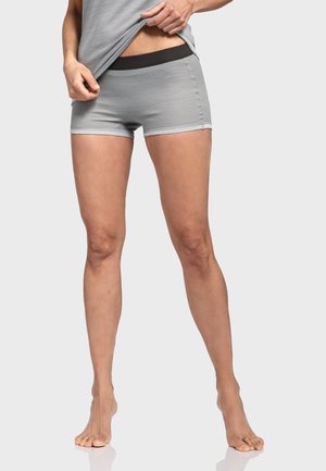 Graue Sportshorts mit einem schwarzen Bund, die ein tailliertes Design und eine glatte Textur aufweisen, präsentiert von einem stehenden Modell.