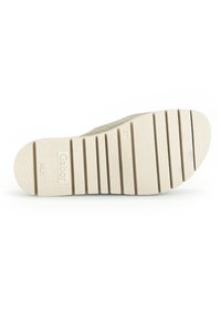 Semelle de chaussure en caoutchouc de couleur crème avec des rainures horizontales et des motifs de texture pour une meilleure adhérence, portant une impression de logo.