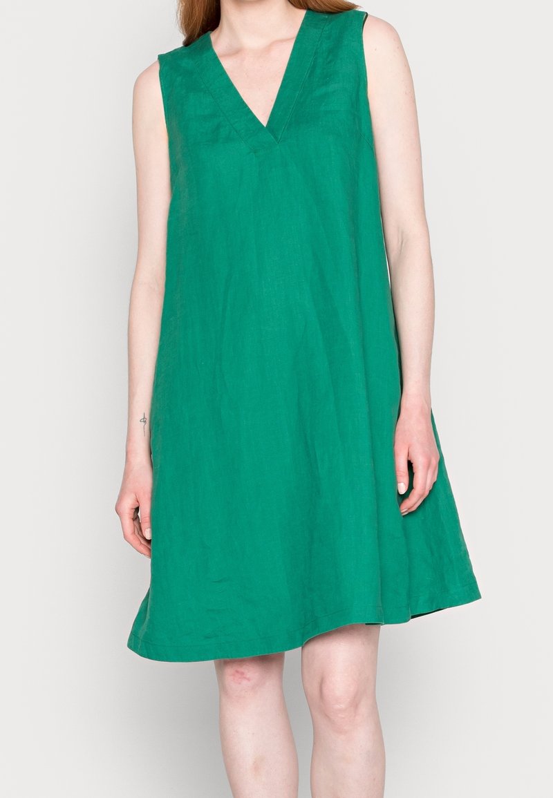 Zielona sukienka bez rękawów z dekoltem w kształcie litery V, wykonana z teksturowanej tkaniny, o luźnym kroju i długości zakończonej przed kolanem.