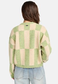 Wollen blend oversized trui met een beige en groene geblokte patroon, geribbelde zoom en een ronde halslijn. Label zichtbaar aan de achterkant.