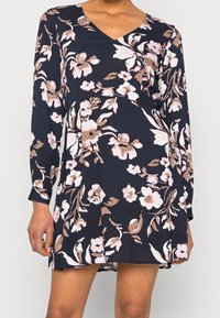 Vestito floreale con base blu navy, caratterizzato da fiori rosa e beige. Maniche lunghe, scollo a V e silhouette svasata. Tessuto dalla texture morbida.