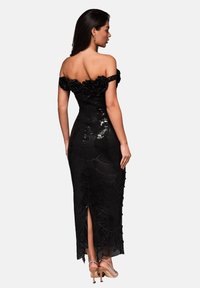 Černé šaty bez ramínek s květinovými akcenty, zdobení flitry, přiléhavý střih, boční rozparek a texturované detaily po celém povrchu.