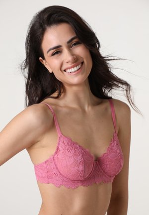 Bralette in pizzo rosa con design floreale, bordi scallop e spalline regolabili, che mette in evidenza una consistenza morbida e dettagli delicati.