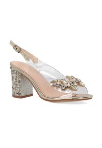 Heldere slingback hak met een decoratieve strassversiering, metalen gouden accenten en een getextureerde blokhak met edelstenen.