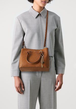 Brūnas ādas rokassoma ar strukturētu formu, dubultām rokturiem un noņemamu plecu siksnu. Iespēro dekoratīvu atslēgu piekariņu un logotipa detaļu.