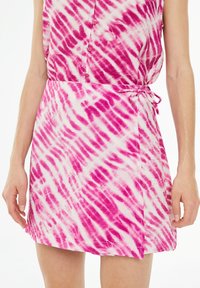 Pink and white tie-dye dress with a button-up front, adjustable side tie, short length, and soft texture. Features a relaxed fit design.