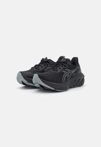 Chaussures de sport noires avec une tige texturée, ornées d'accents gris contrastants, à bout rond et semelles rembourrées avec un motif.