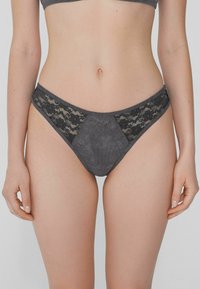 Ropa interior gris que presenta una combinación de tejido suave y delicado encaje negro en los laterales, con forma triangular y cinturilla.