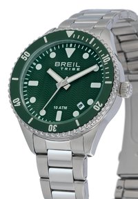 Montre-bracelet en métal argenté avec lunette et cadran vert, marqueurs blancs, trois aiguilles, fenêtre de date indiquant le 8, et logo "Breil Tribe".