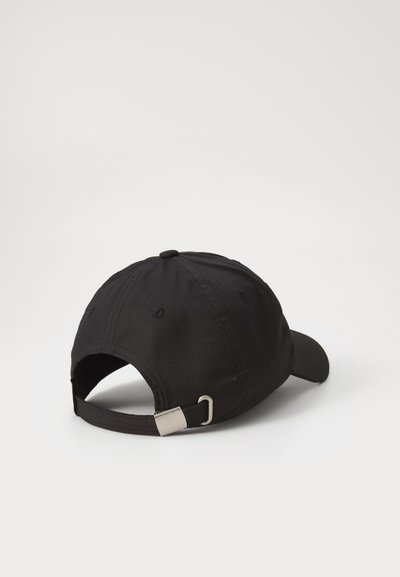 Casquette de baseball en coton noir avec un bord incurvé, sangle ajustable à l'arrière et détail en métal argenté. Texture lisse.