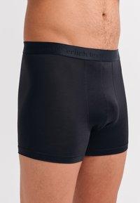 Schwarze Boxershorts aus einem glatten, dehnbaren Material. Verfügt über einen weichen elastischen Bund mit dem Text "erlich textil" in einer tonal abgestimmten Farbe.