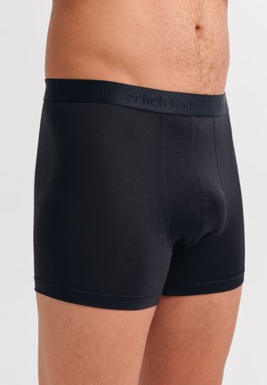 Schwarze Boxershorts aus einem glatten, dehnbaren Material. Verfügt über einen weichen elastischen Bund mit dem Text "erlich textil" in einer tonal abgestimmten Farbe.
