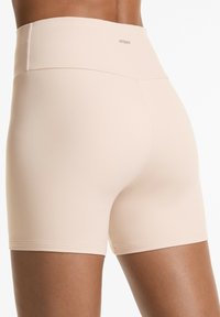 Beige höga shorts gjorda av ett mjukt, stretchigt material. Har en bred midja och en sömlös, figurnära design. Inga synliga sömmar.