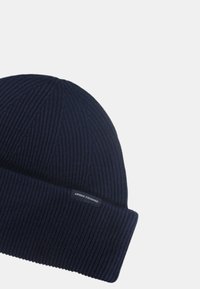 Berretto a maglia a coste di colore blu navy con risvolto pieghevole. Presenta un piccolo etichetta cucita con la scritta "Armani Exchange" sul lato. Tessuto morbido, materiale caldo.
