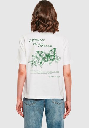Biała bawełniana koszulka z zielonym motylem i kwiatowymi wzorami na plecach, z napisem "Flutter & Bloom" w eleganckiej czcionce.