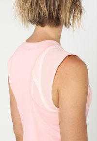 Top rosa sin mangas con escote redondo, que presenta un panel de malla en contraste en la espalda y detalles sutiles de costura.