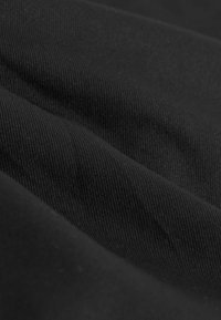 Juodas audinys su grioveliais, rodo sklandžius, banginius raukšlėjimus. Paviršius yra vienodas ir nepermatomas, be matomų raštų ar akcentų.