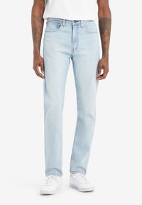 Ljusblå denimjeans med raka ben, femfickdesign och subtila blekningar. I kombination med vita sneakers för kontrast.