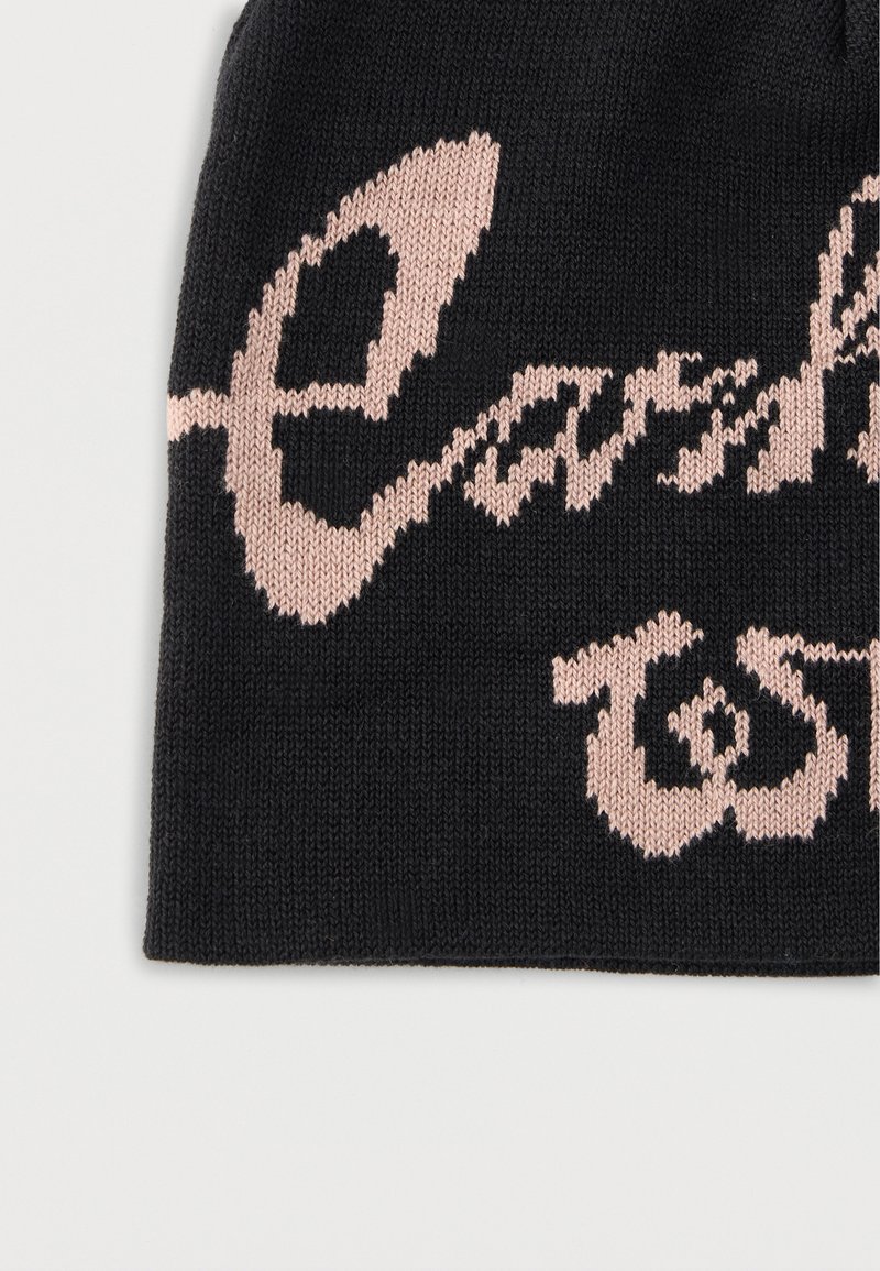 Schwarzer Strickstoff mit teilweise sichtbarem rosafarbenem kursivem Text, der die Buchstaben "ea" und "TS" zeigt.