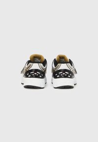Αθλητικά παπούτσια σε ασπρόμαυρο με υφή από πλεκτό δίχτυ, χρυσές λεπτομέρειες και μαλακή σόλα. Φέρουν εμφανές λογότυπο στο πίσω μέρος.