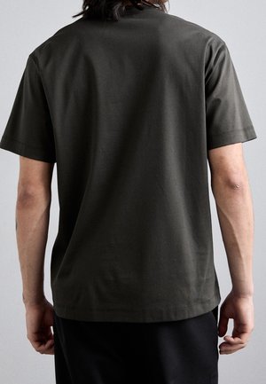 Ciemnozielona bawełniana koszulka z krótkimi rękawami, okrągłym dekoltem i luźnym krojem. Charakteryzuje się gładką fakturą i prostym wzornictwem.