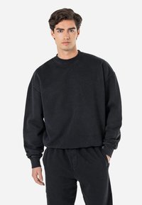 Sort bomulds sweatshirt med rund hals og løs pasform, ribbede manchetter og kant. Har et tone-i-tone logo prægning på brystet. Kan kombineres med matchende bukser.