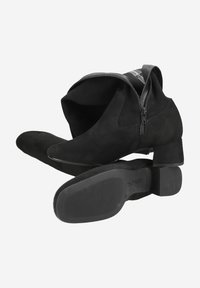Stivaletti in suede neri con tacco basso, dotati di cerniera laterale e design minimalista. La suola è strutturata per garantire aderenza.