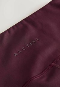 Bordo aktivna tkanina s glatkom teksturom, s utisnutim logom "ACTIVE" i minimalnim detaljima šivanja.