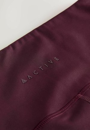 Bordeauxkleurige activewear stof met een gladde textuur, voorzien van een reliëf "ACTIVE" logo en minimale stikdetails.