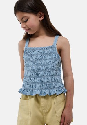 Haut en denim bleu clair avec un corps smocké, des bretelles larges et un ourlet volé. Associé à un short beige, soulignant un look d'été décontracté.