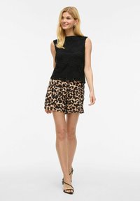 Black textured top with floral pattern, paired with beige shorts featuring a leopard print. Black strappy sandals complete the outfit.