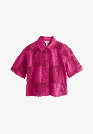 Blouse en dentelle fuchsia à manches courtes avec motifs floraux au crochet, fermeture boutonnée à l'avant et col pointu.