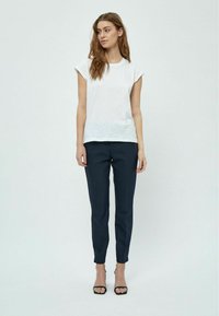 T-shirt bianco a maniche corte, con collo a giro, abbinato a pantaloni blu slim-fit e sandali neri con tacco. Tessuto morbido con un taglio classico.