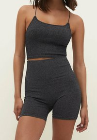 Crop top court gris côtelé avec fines bretelles, associé à un short taille haute, présentant un design sans coutures et une coupe ajustée.