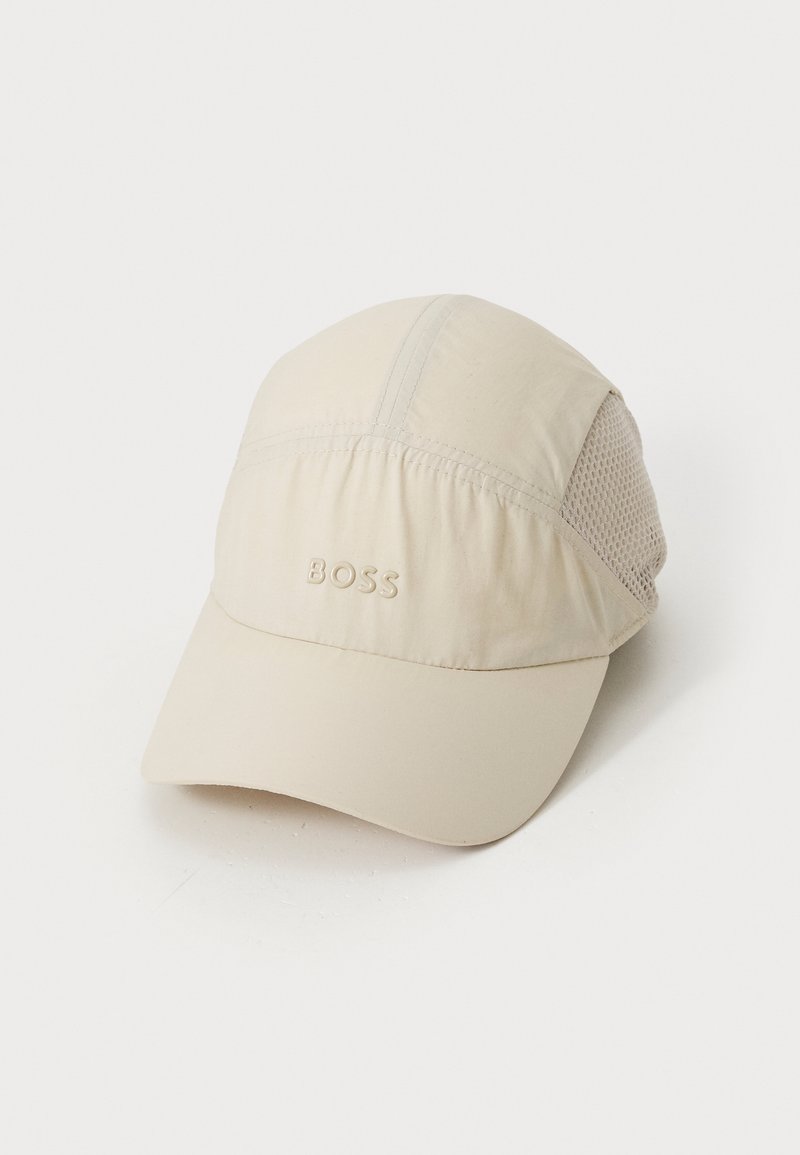 Beež spordimüts pehme kangast kehapäraga, silmadega külgpaneelide ja kaardus visooliga. Ees on reljeefne "BOSS" logo.