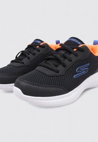 Schwarze Skechers-Sneaker aus Netzstoff mit blauem Logo, orangefarbenem Innenfutter, schwarzen Schnürsenkeln und weißen Sohlen, nebeneinander auf hellem Hintergrund dargestellt.