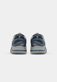 Blue and gray sneakers with a cushioned sole, featuring a textile upper and rubber outsole. Branding in orange on the back and side.