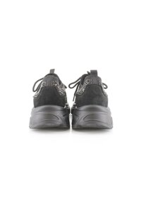 Zapatillas negras con suelas gruesas, parte superior de tejido de punto con pequeños puntos blancos y lengüetas en el talón, vistas desde atrás.