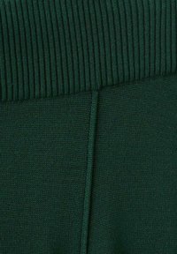 Tejido de punto verde oscuro con una cinturilla acanalada, que presenta una textura suave y un ligero estiramiento, adecuado para ropa casual o de descanso.