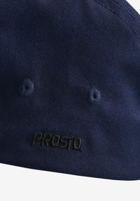 Granatowa czapka z teksturowanej tkaniny, z czarnym haftowanym logo "PROSTO" z przodu oraz dwoma otworami wentylacyjnymi.