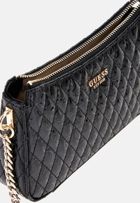 Schwarze, gepolsterte Handtasche aus Synthetik mit goldenen Beschlägen, ausgestattet mit einem Reißverschluss und einer Kettenriemen. Logo auf der Vorderseite, geprägt mit Rautenmuster.