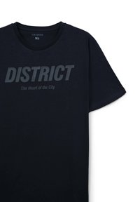 T-shirt in cotone navy a maniche corte, con testo in grassetto "DISTRICT" e sottotitolo "Il Cuore della Città" in una tonalità più scura.